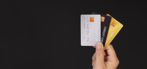 手は黒い背景に分離された 3 つのクレジット カードを保持しています。