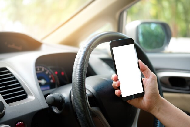 Hand is holding a touch phone with isolated screen in the car.