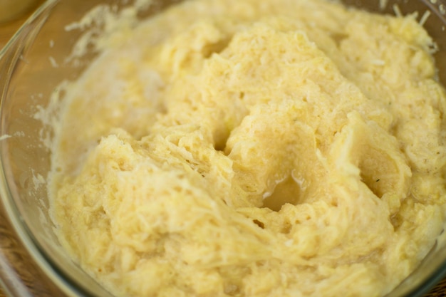 The hand is kneading grated potatoes to make dough