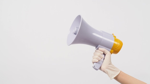 Hand is megafoon vasthouden en medische handschoen dragen op witte achtergrond.