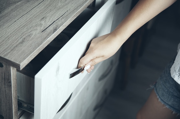 A hand is opening a wooden drawer