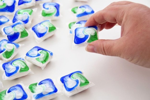 A hand is picking up a pile of laundry detergent.