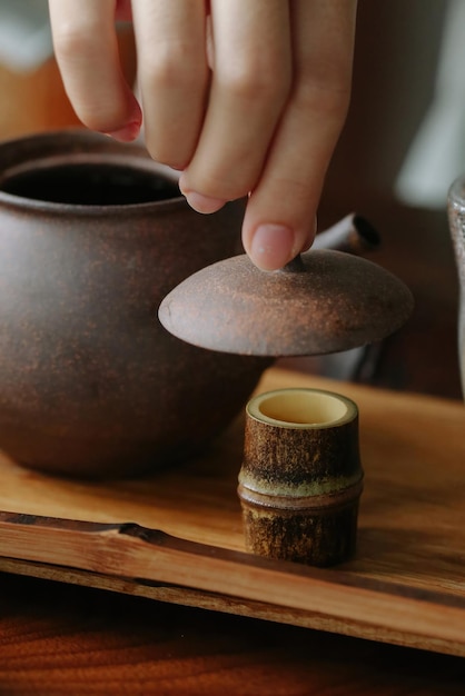 A hand is placing a cup of tea on a wooden table Make tea and enjoy it at home while relaxing