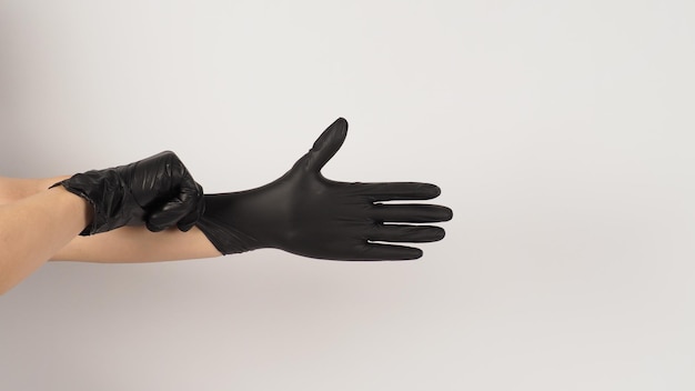 The hand is pulling black latex gloves on white background