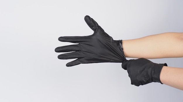 Hand is pulling black latex gloves on white background