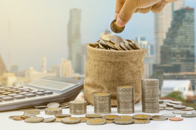 The hand is putting coins into bag and  accummulate in column that represent money saving or financial planning idea for economy.