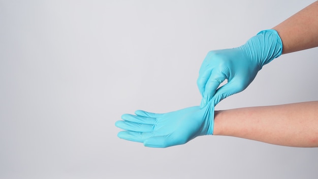 Hand is remove blue surgical gloves by grasp the outside of one glove on white background.