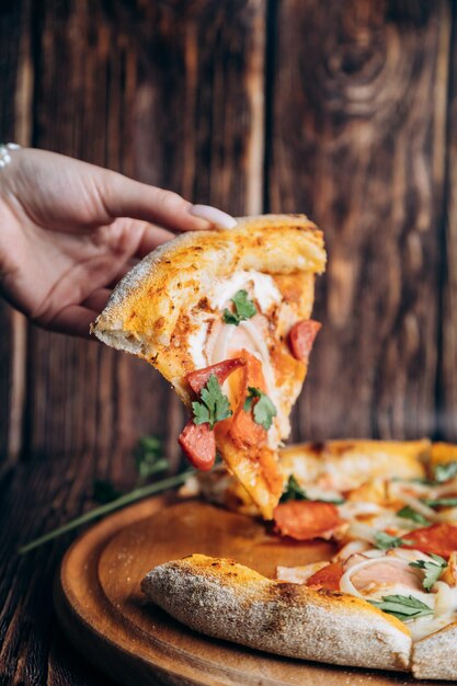 A hand is taking a slice of pizza from a pizza pan.