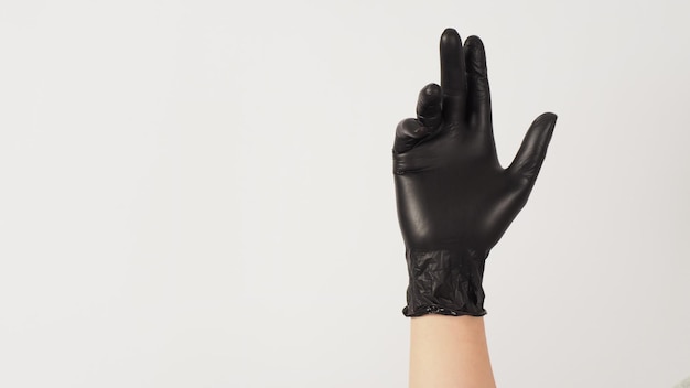 手は白い背景に黒のラテックス手袋を着用します。
