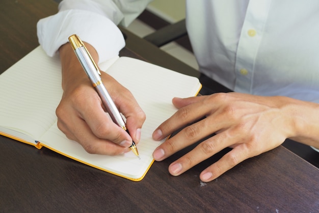 The hand is writing on notebook