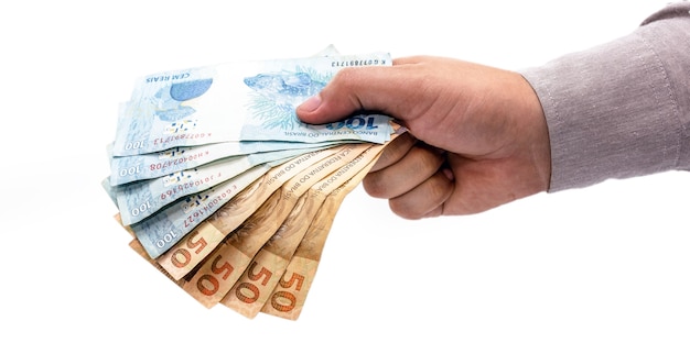 Рука на изолированном белом фоне, предлагая деньги Бразилии, банкноты сто пятьдесят реалов, бразильскую экономику.