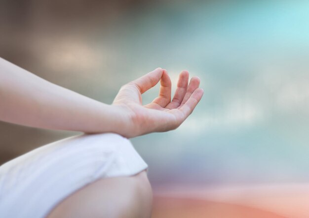 Hand and knee of meditating woman against blurry blue brown background