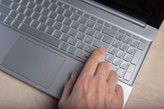 Hand on laptop keyboard tapping and pressing button with finger closeup