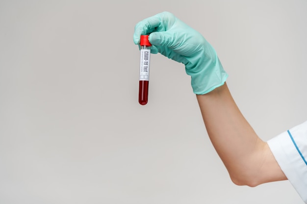 Hand in latex glove holding blood in test tube close up