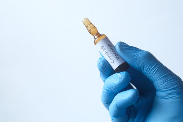 Hand in latex gloves holding coronavirus vaccine isolated on white .