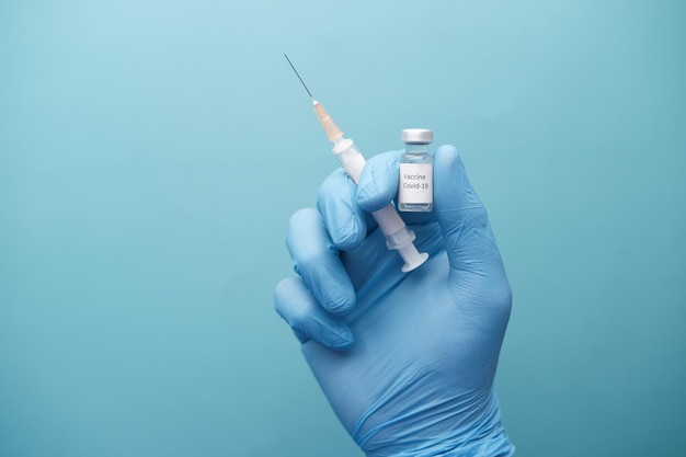 Hand in latex gloves holding glass ampoule vaccine with copy space