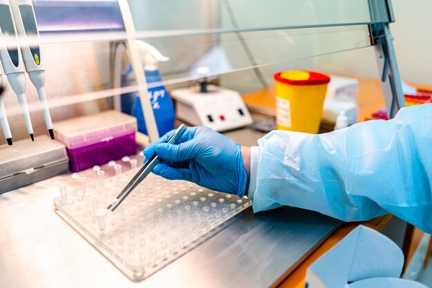 Hand in latex gloves uses tweezers to put probes on tablet. Laboratory concept of analazying blood and urine. closeup.