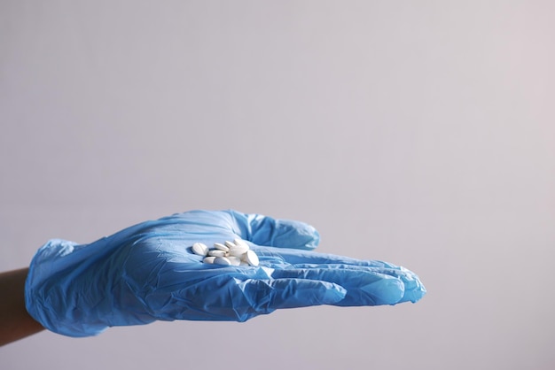 Hand in a latex gloves white medical pills on hand