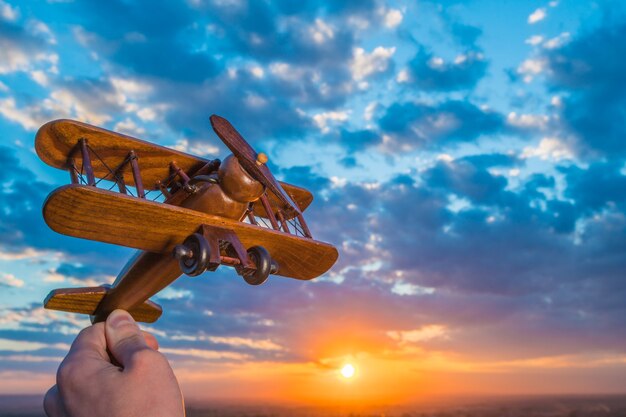 Photo the hand launch toy plane on the background of a sunset