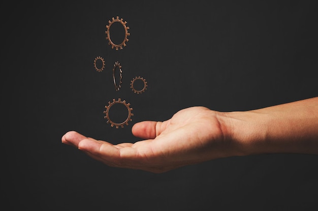 Hand and levitating gears on a gray background. Concept progress, development, innovation and technology.