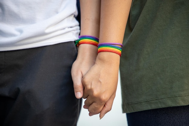 Foto mano di donne lgbt che tengono insieme al nastro arcobaleno il concetto di simbolo di orgoglio lgbt persone lgbtq campagna per i diritti lgbt matrimonio dello stesso sesso