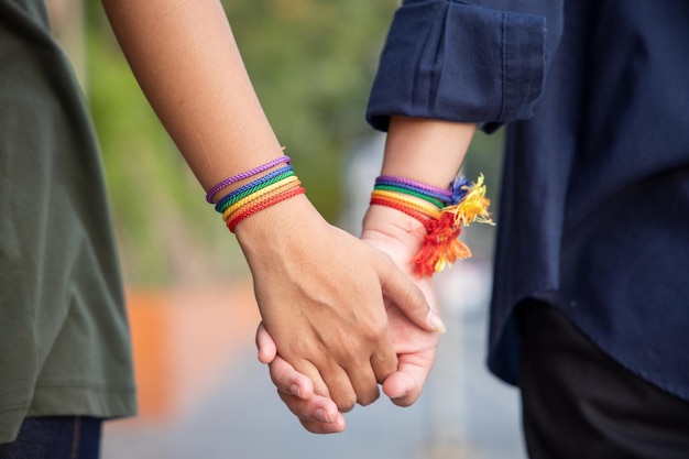 Mano di donne lgbt che tengono insieme al nastro arcobaleno il concetto di simbolo di orgoglio lgbt persone lgbtq campagna per i diritti lgbt matrimonio dello stesso sesso