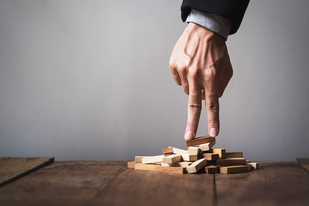 Hand liken business person stepping up a toy wooden block to goal