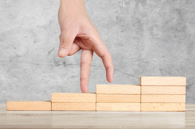 Hand liken person stepping up wood block stacking as step stair