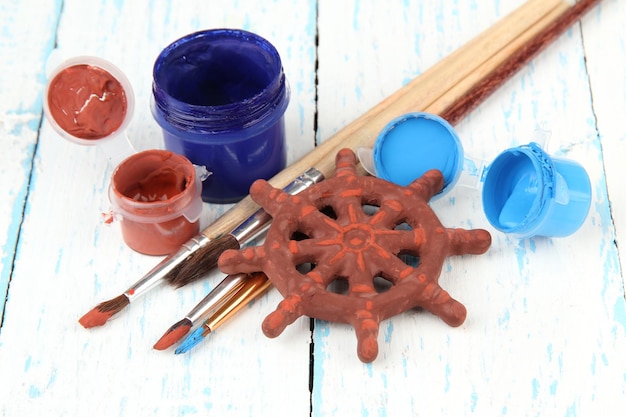 Photo hand made ceramic wheel and color paints on wooden table