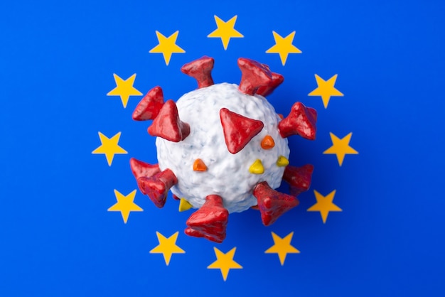 Фото Сделанная вручную модель covid-19 посреди флага евросоюза