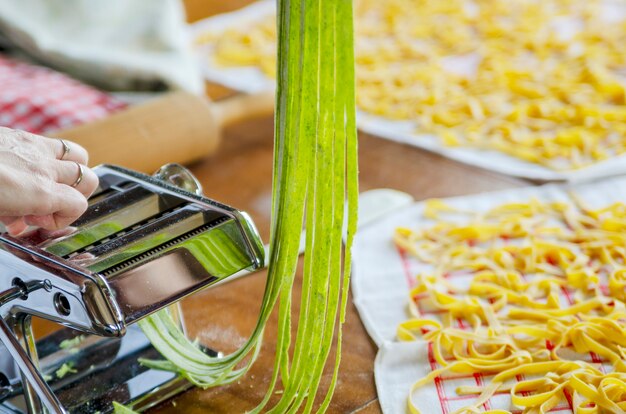 Hand made green spinach pasta spaghetti with pasta machine maker.