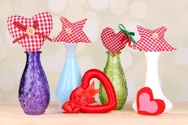 Hand-made textile hearts and stars on wooden table, on light background