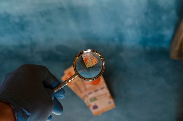 hand magnifying glass on 1000 peso bills marking the devaluation of the Argentine currency