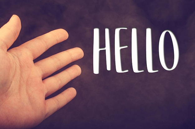 Photo hand making a hello welcome gesture on dark background