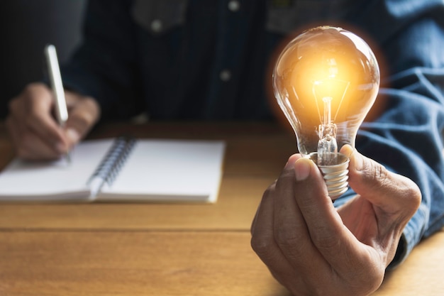 Hand of male holding a light bulb and copy space for accounting