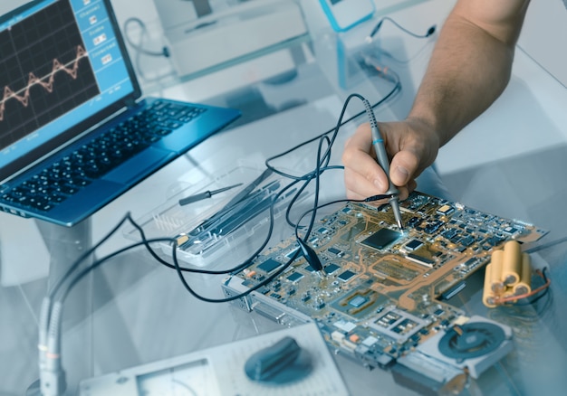 Hand of male tech testing motherboard