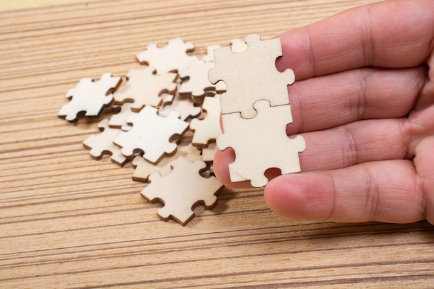 Hand of male trying to connect pieces of jigsaw puzzle