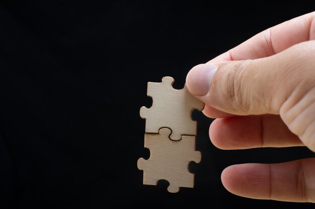 Hand of male trying to connect pieces of jigsaw puzzle