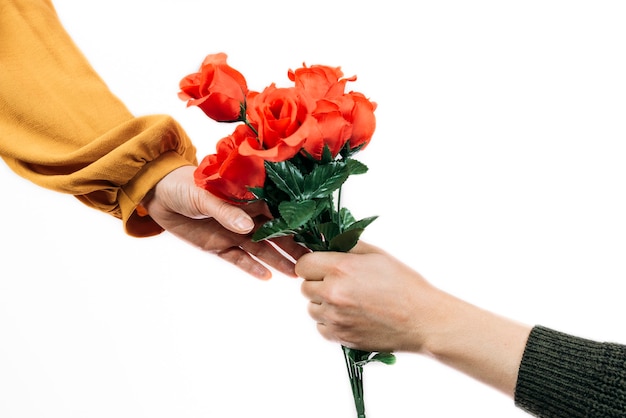 Mano di un uomo che dà un mazzo di fiori rossi a una donna