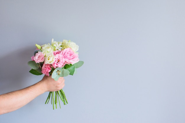 Hand of the man holding a beautiful bouquet of flowers