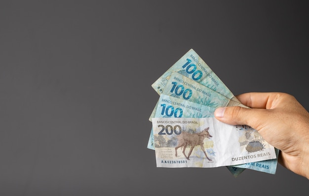 Hand of a man holding Brazilian banknotes