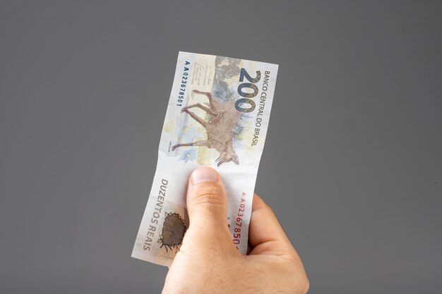 Hand of a man holding Brazilian Reais banknotes