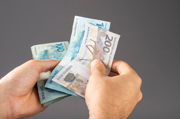 Hand of a man holding Brazilian Reais banknotes