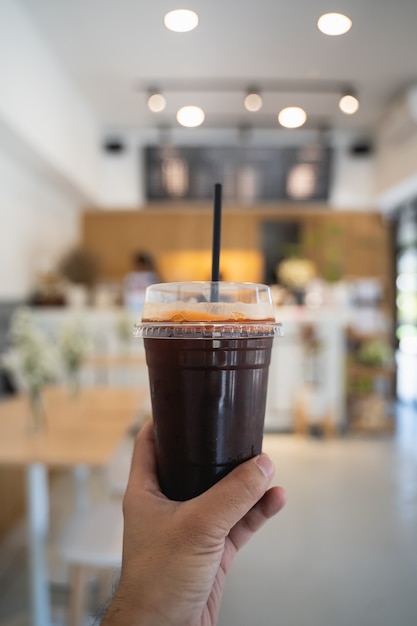 Hand man holding a cup of ice coffee in the cafe