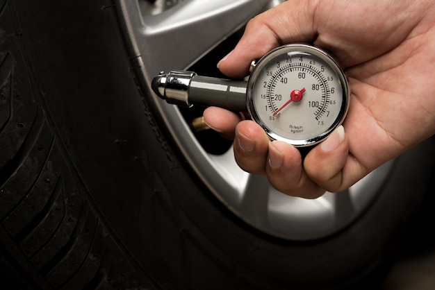 Hand of man holding gauge measurement pressure checking tire of car transportation 