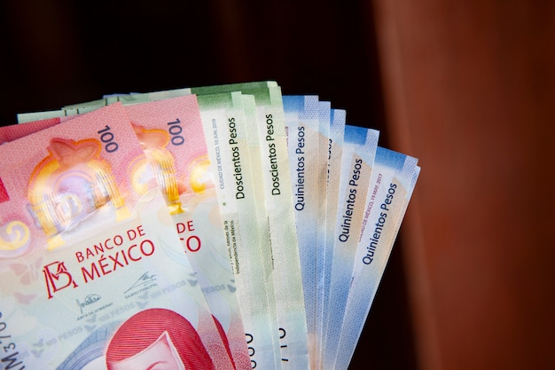 Рука человека, держащего новые банкноты мексиканского песо