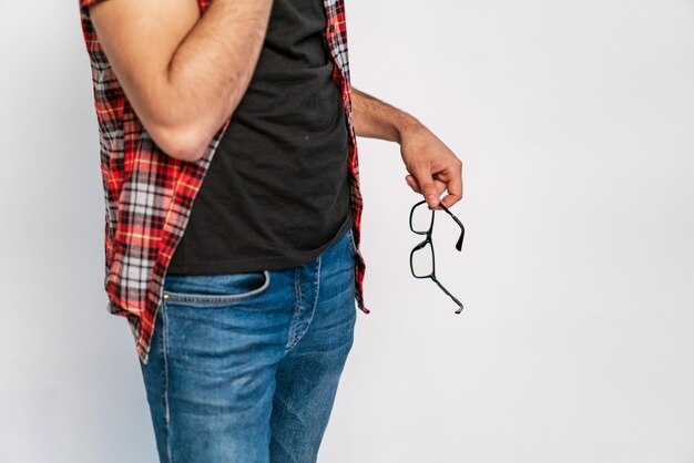 Hand of a man holds a model of glasses with a black frame for work on a white background Closeup