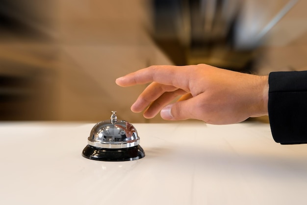 La mano di un uomo utilizzerà un campanello d'albergo vintage con effetto sfocatura movimento