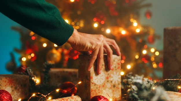 Photo hand of a man is preparing the christmas table with gift