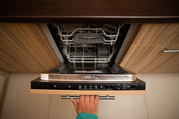 hand of man opening dishwasher in apartment